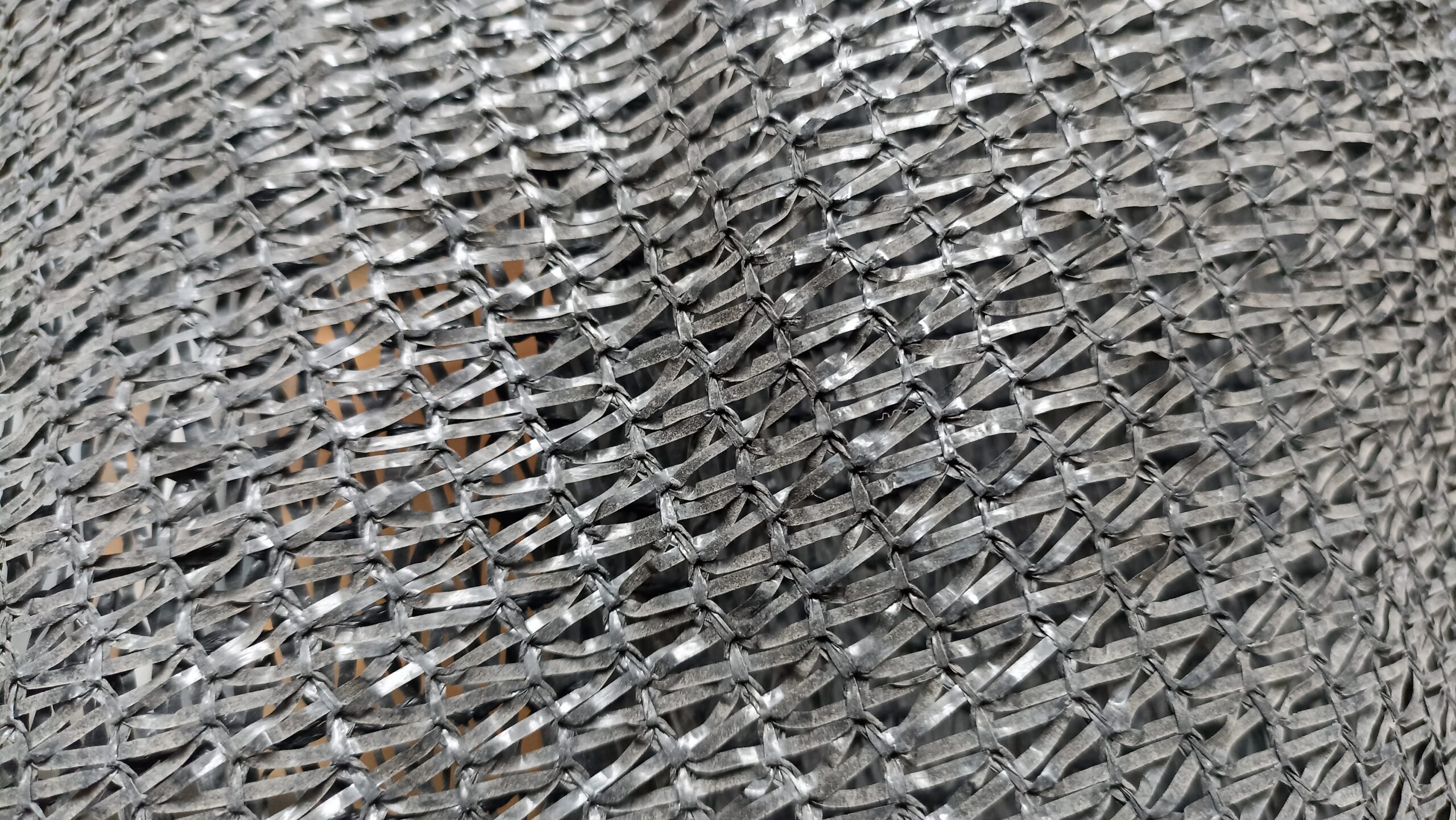 Close up texture of woven black plastic mesh netting used for shade, agriculture, or construction safety fencing